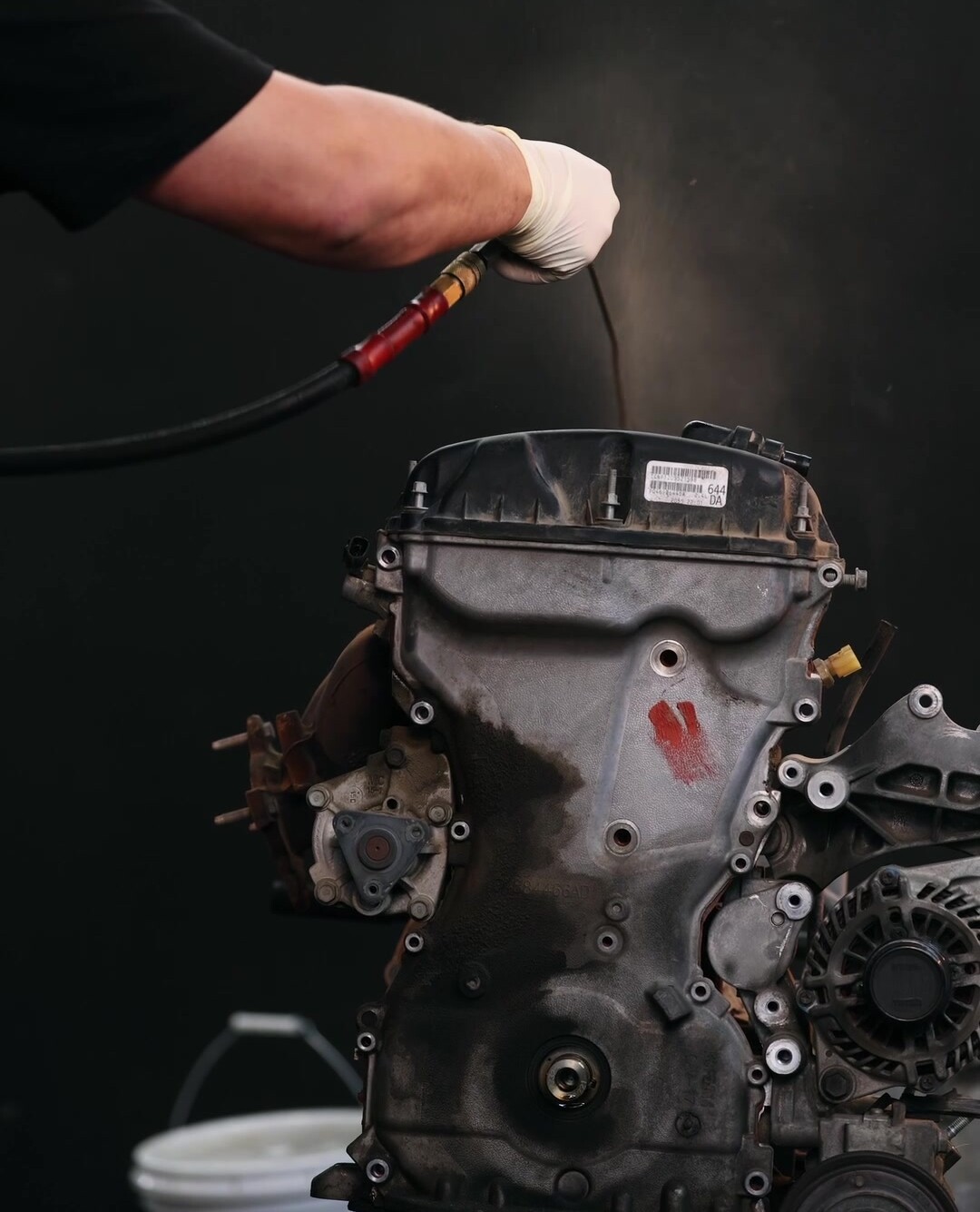 Las manos de un mecánico dentro de un motor abierto en el taller de Service99 — el tipo de trabajo intenso donde la mano de obra siempre es lo que asusta.